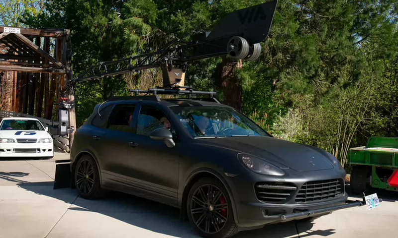 students filming a drift car from inside another car that has a robot arm and camera on the roof