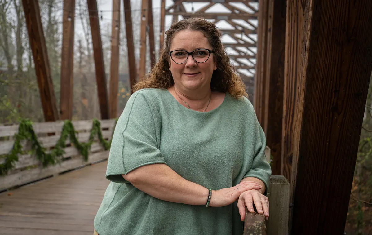 Emilia Reynolds poses for a photo on a bridge in a green shirt. 