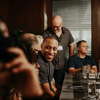 Mario smiling with people at a dinner table