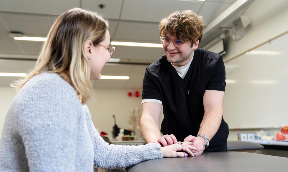 Connor Shobe smiling while treating a patient's hand
