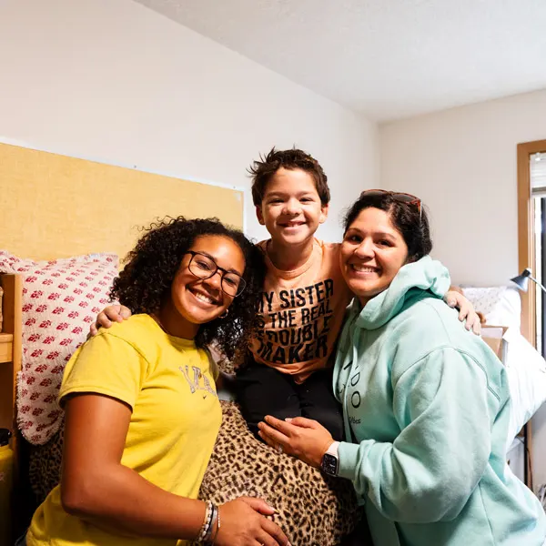 A student poses for a photo with her mom and brother during Move-in