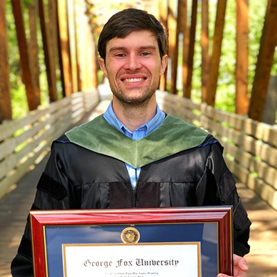 Matt Roth holding his diploma from George Fox