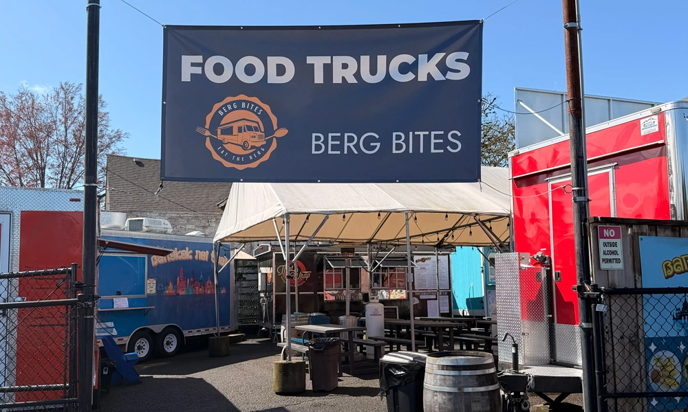 entrance to a group of food trucks with a banner overhead, reading 'Food Trucks - Berg Bites'