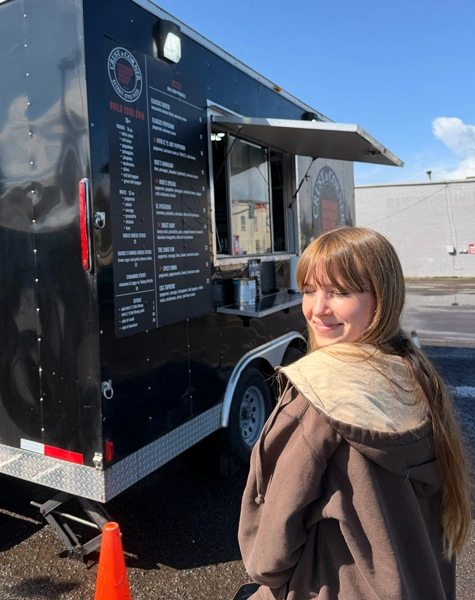 Grace standing in front of the Crust and Corner food truck