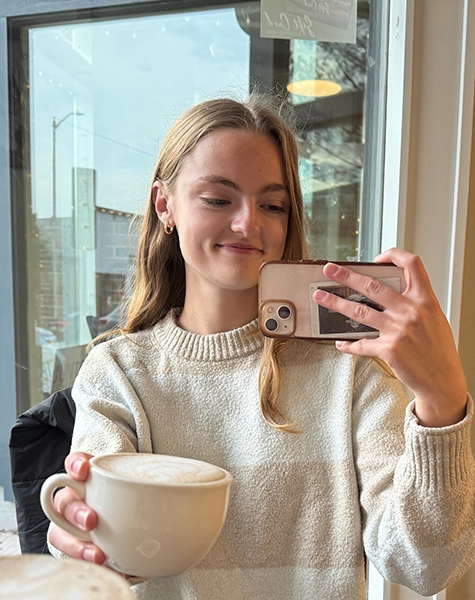 Grace's friend smiling and holding a coffee