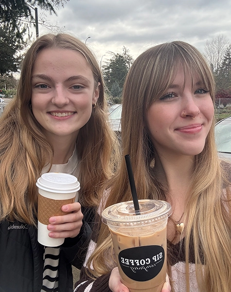 Grace and Grace's friend smiling and taking a selfie while holding their coffee