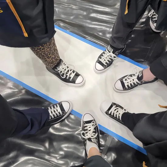 The cohort shows off their converse shoes arranged in a circle on the ground
