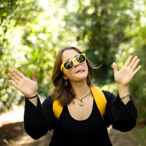 A female student with gold sunglasses makes a silly face