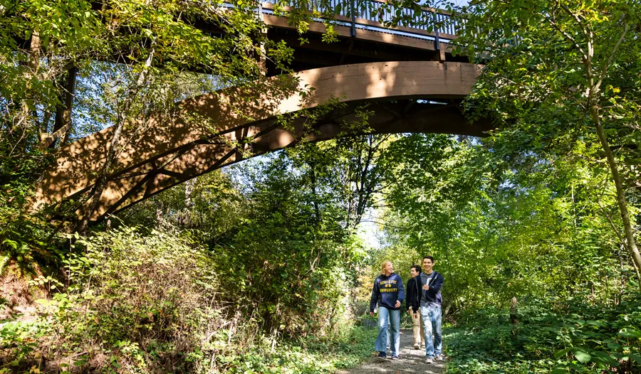 3 George Fox Students walk the trails under a bridge in the canyon
