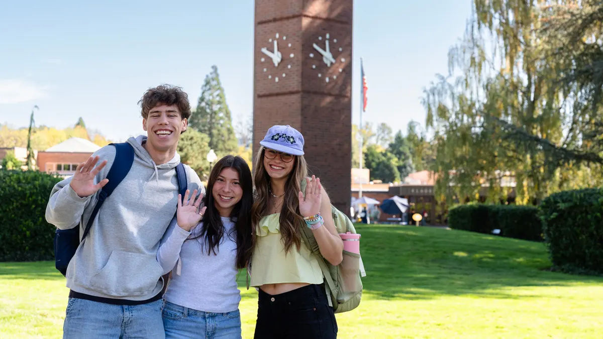 Two George Fox Student sit below the Centennial Tower on a sunny day