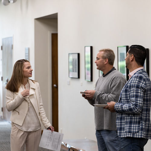 Three individuals talk in a hallway