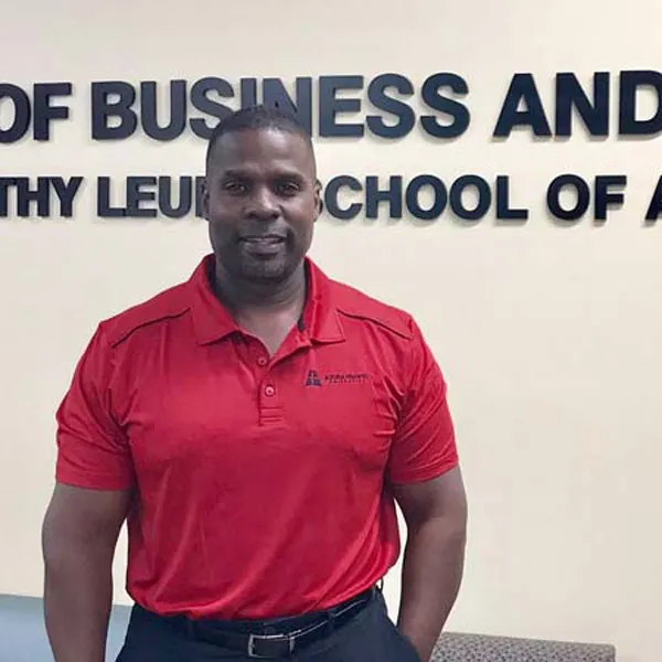 Marlon Ware stands in front of a School of Business School sign