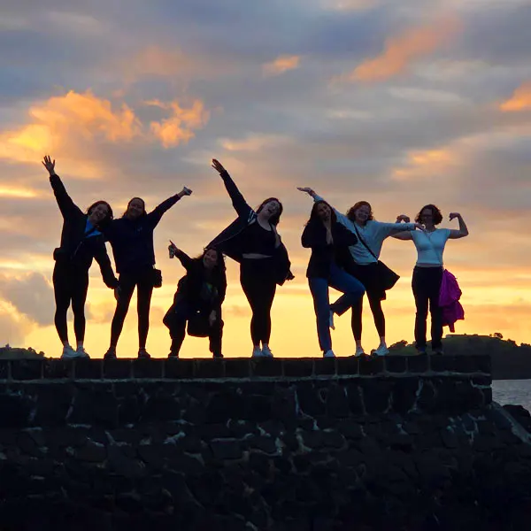 7 Students pose in front of a sunset in New Zealand