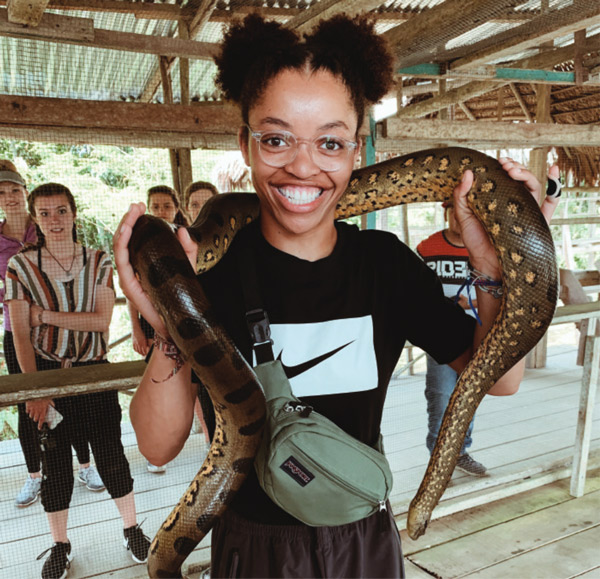 A girl smiling with a snake draped over her shoulders