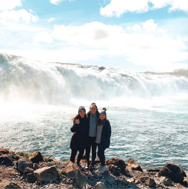 students in pose in front of a waterfall