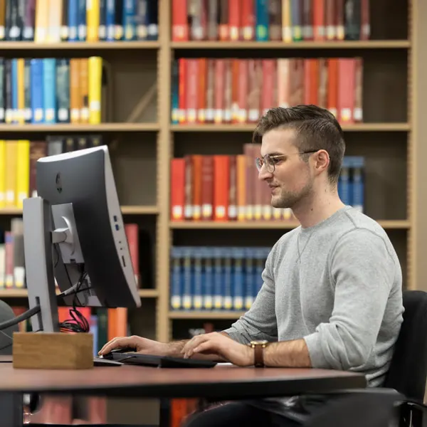 A student sits in the library on a computer