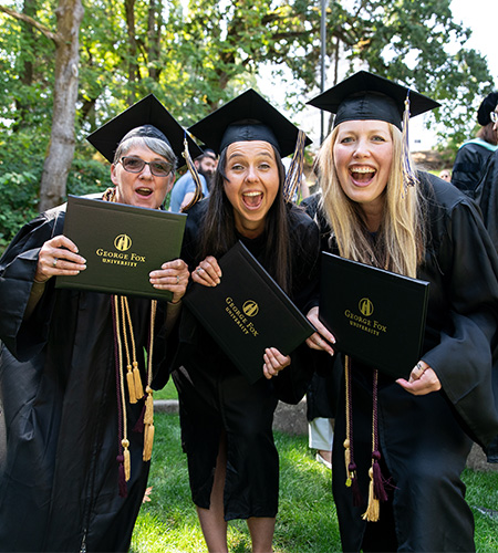 three graduates celebrating with their diplomas