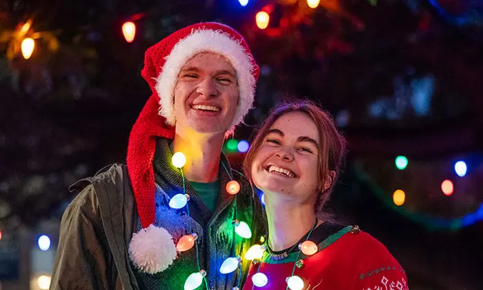 Two George Fox students smile with Christmas lights wrapped around them