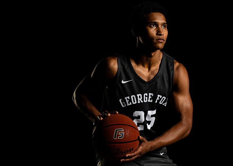 Male basketball player in uniform holding a basketball and looking intensely to the right