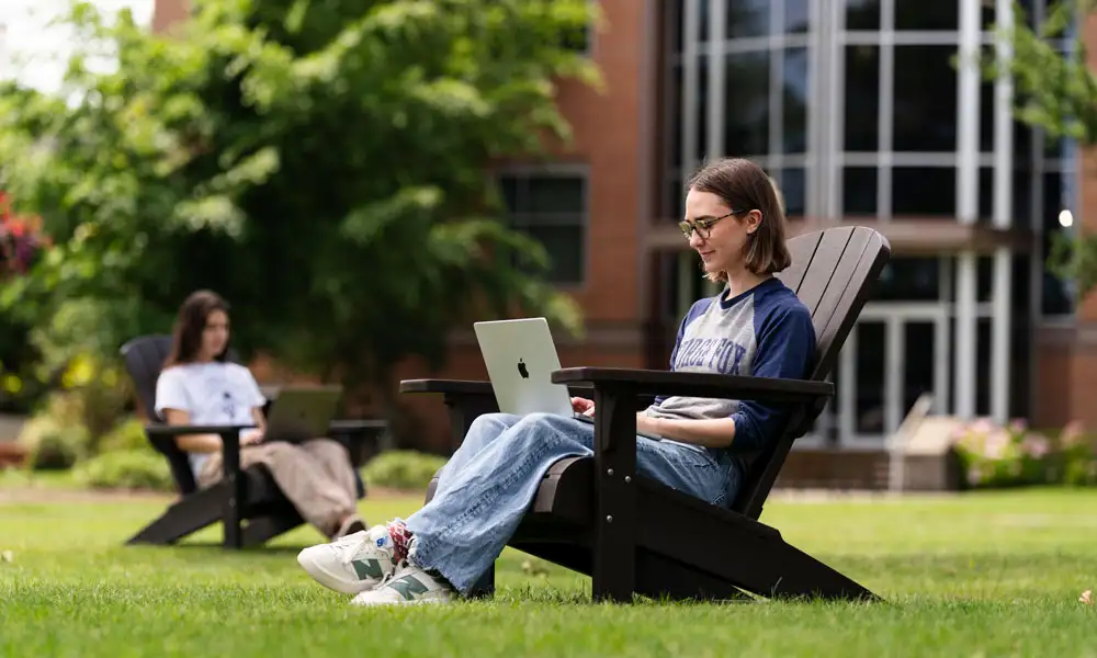 A student working on her laptop on an outdoor chair