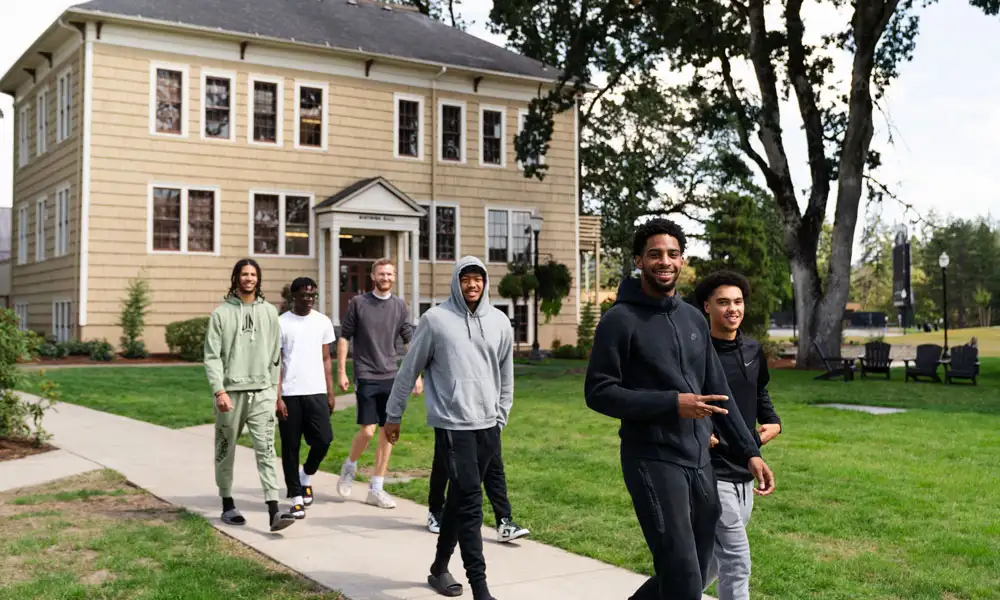 Students walking through campus smiling at the camera
