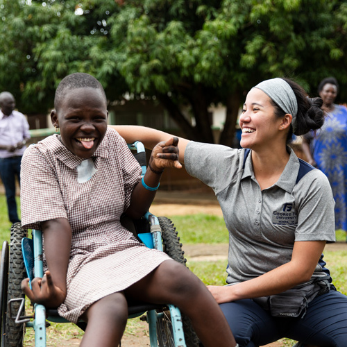 Photo of a student laughing with a child in a wheelchair