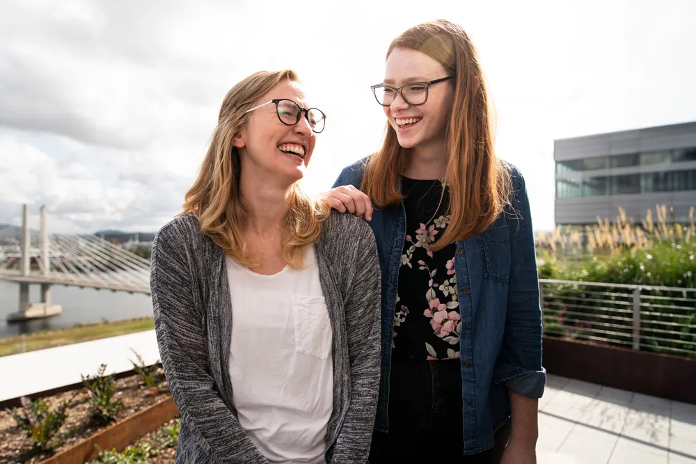 Photo of Quinlan Morrow and Brittany Smith laughing besides a bridge in Portland, OR