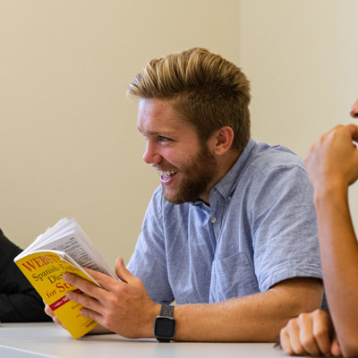 Student holding a Spanish to English dictionary in class laughing