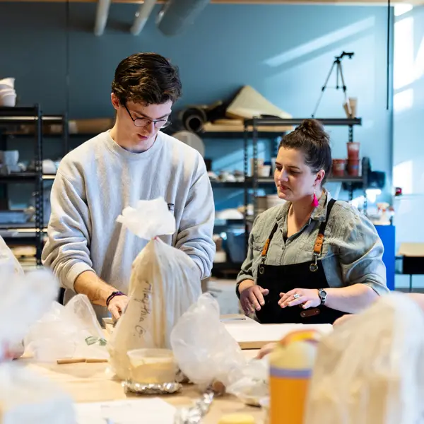 Ceramics professor helps a student with his work