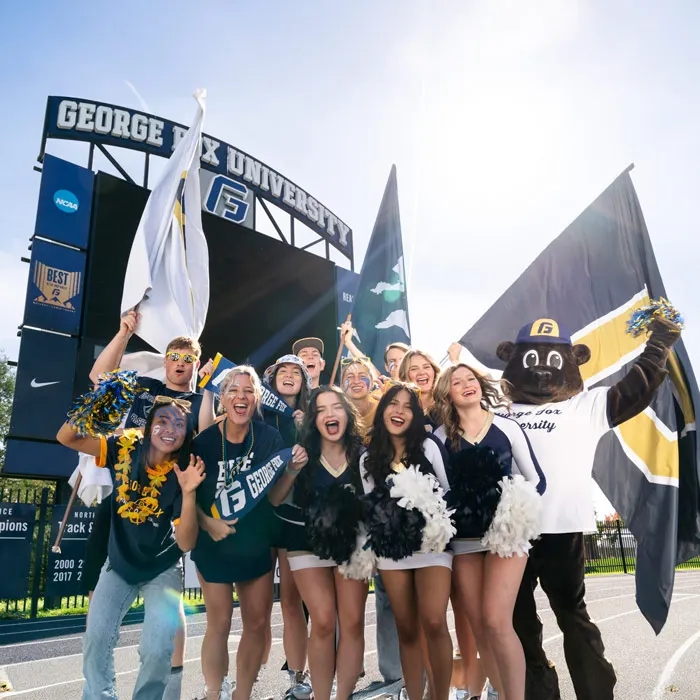 Group of students cheer outside the stadium on campus on a sunny day