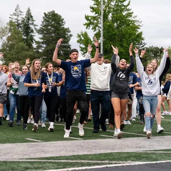 A crowd of undergrad students cheer on the football field