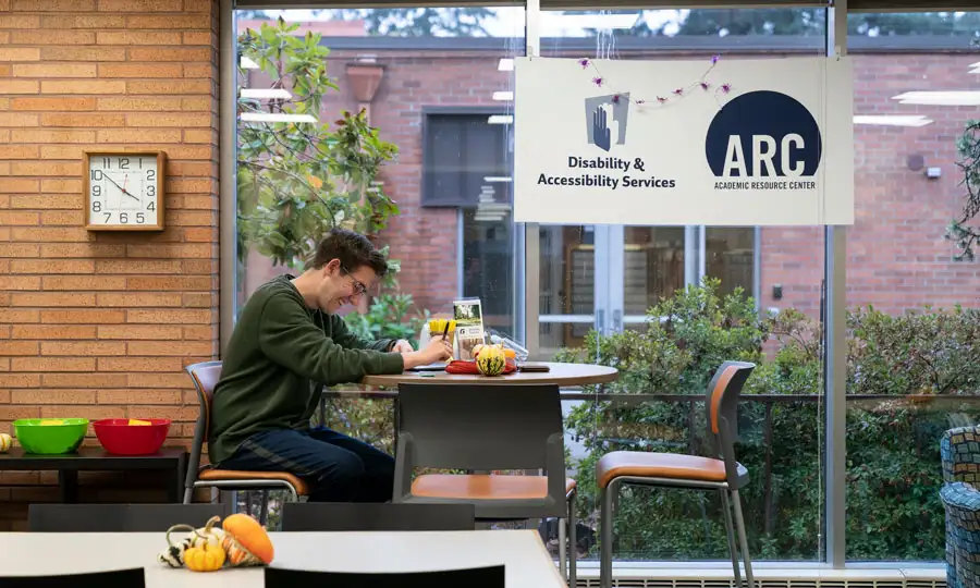 A student working at a table in front of windows in the ARC