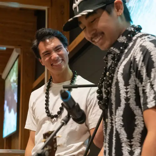 A student smiles while playing an instrument for Hawaii club