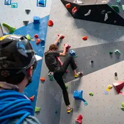 Student climbing the rock wall at Hadlock while another student watches