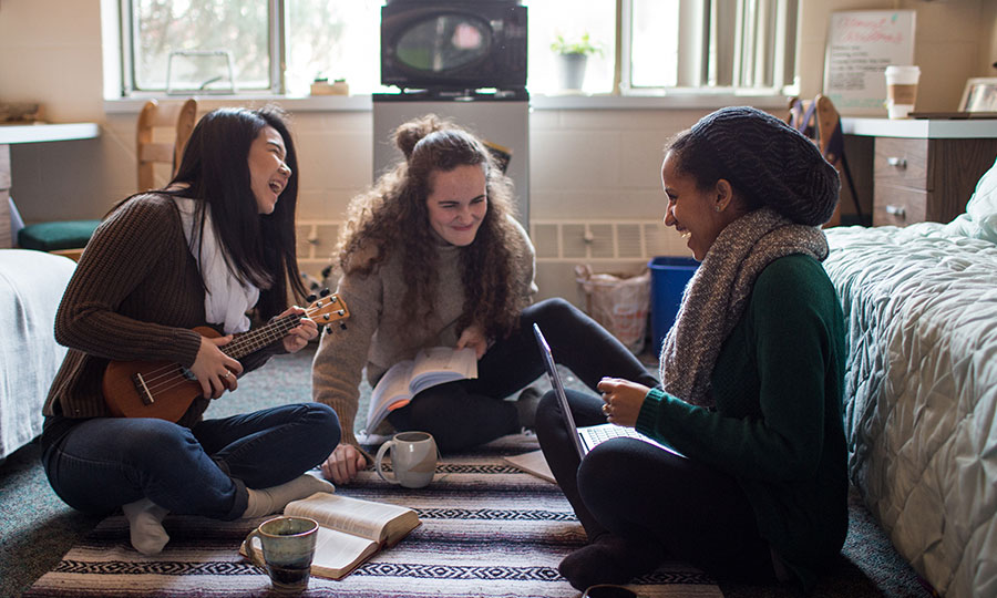 Three students spend time together in a dorm room