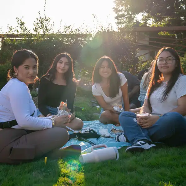 A group of multicultural students sitting on a blanket outside