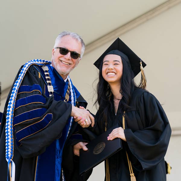 President Dr. Robin Baker shakes a graduate's hand