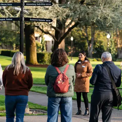 Students and family standing around an admissions counselor on the quad who's giving a campus tour