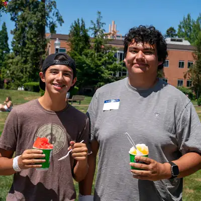 Two students holding Kona ice standing in the quad smiling