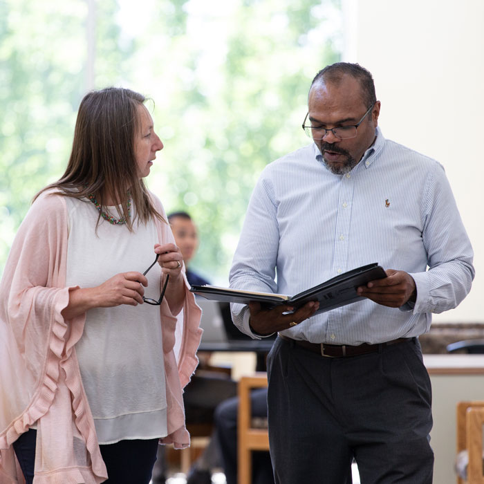 two adults consult over a folder