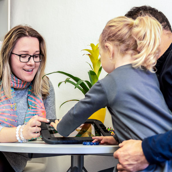 Family counselor directs a father holding his daughter to an iPad on the table