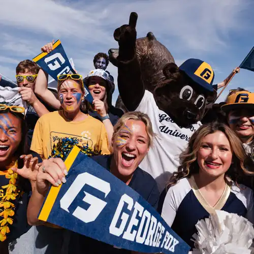 A group of George Fox students cheering with face paint and swag