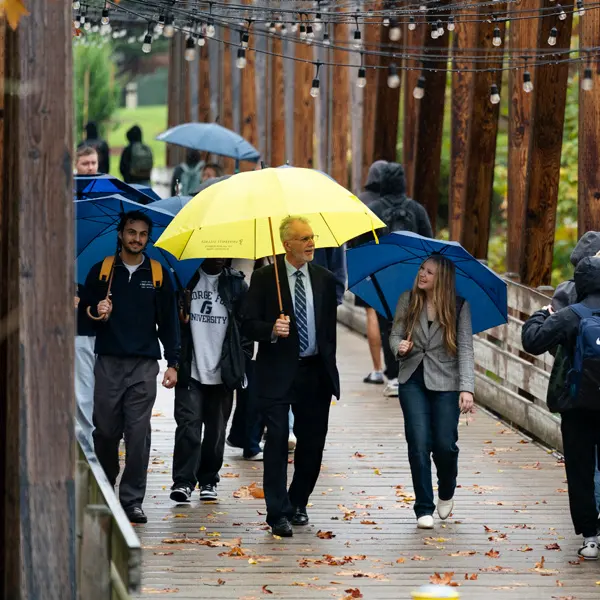 Robin Baker walks with a group of students on campus