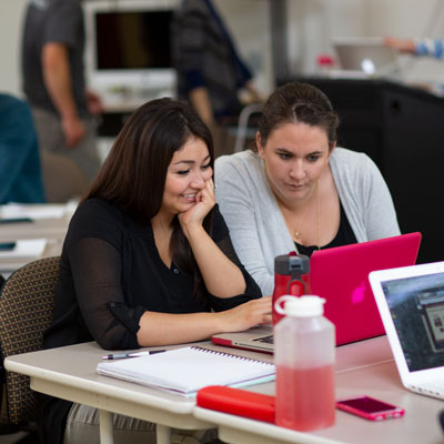 Two MAT student on a pink computer in class