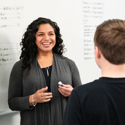 a teacher helping a student at the whiteboard