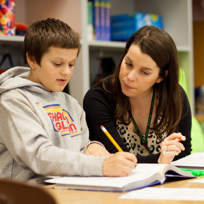 a teacher helps her young student with writing