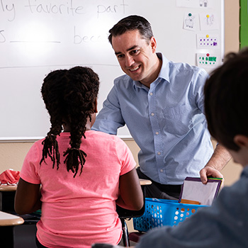 Teacher interacting with student in an elementary school classroom