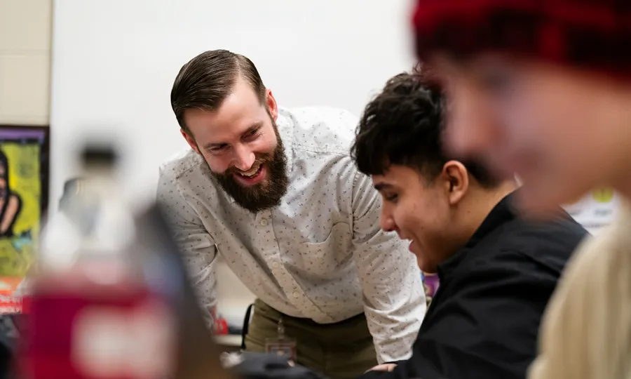 MAT teacher leans over to speak to a high school student