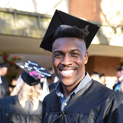 Graduate student smiles in a close up portrait in a grad cap