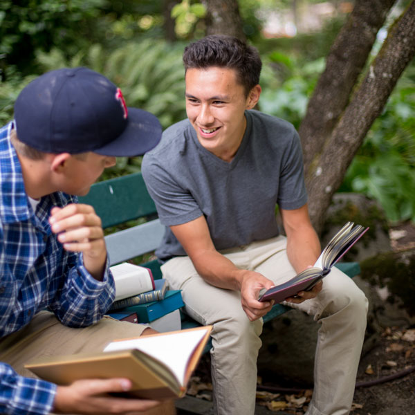 2 students sit outside reading the Bible